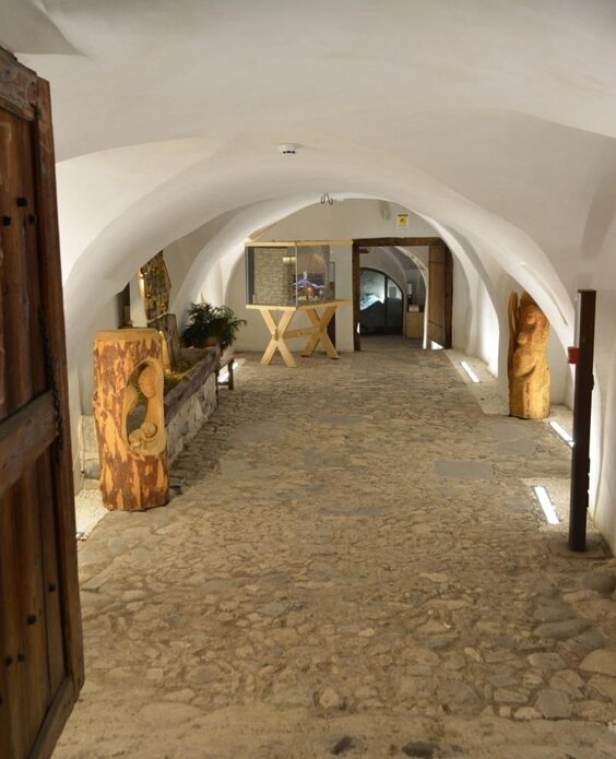 Un corridoio affascinante con pareti bianche e pietre sul pavimento. Le porte in legno si aprono su uno spazio luminoso e accogliente.