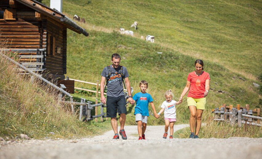 Genitori con bambini passeggiano su strada sterrata mano nella mano