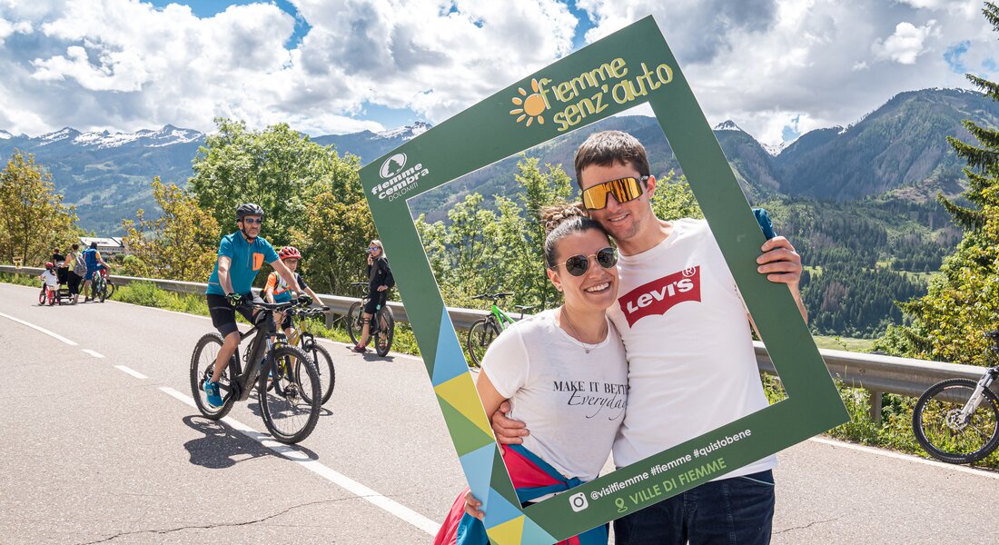 Pedoni si fanno scattare una foto sulla strada statale con la cornice di Fiemme Senz'Auto