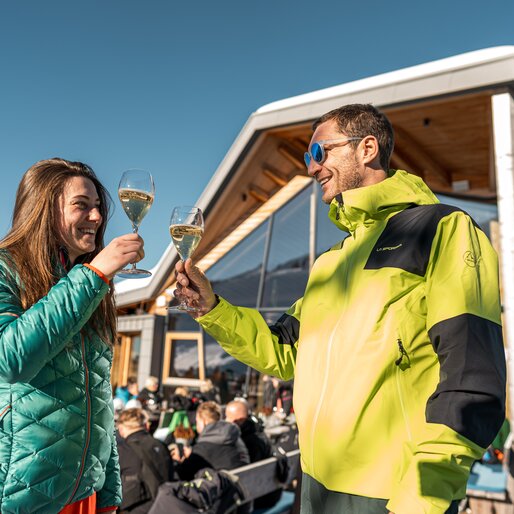 Coppia si gode un calice di bollicine sulla terrazza soleggiata dello Chalet all'Alpe Cermis | © APT Fiemme e Cembra - Mattia Rizzi